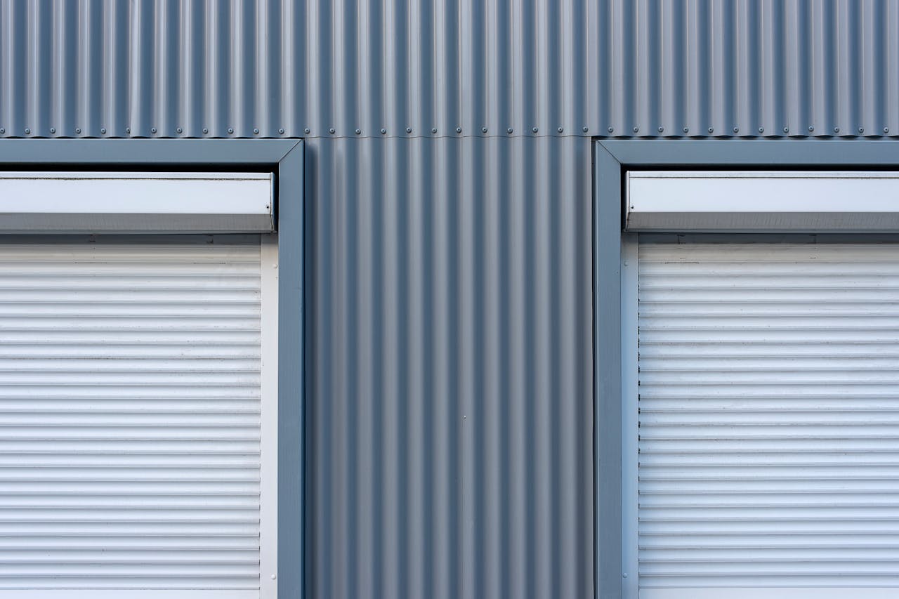 Dual industrial-style roller blinds on a corrugated metal wall for a sleek, modern look.