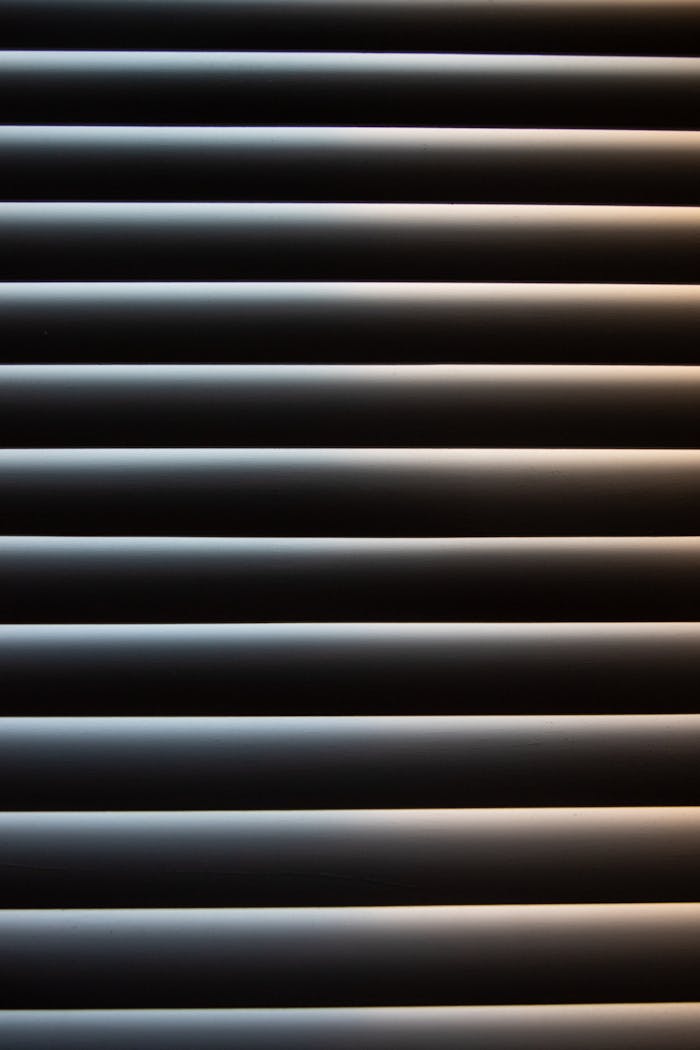 Detail shot of aluminum window shutters with light reflections, creating a modern pattern.